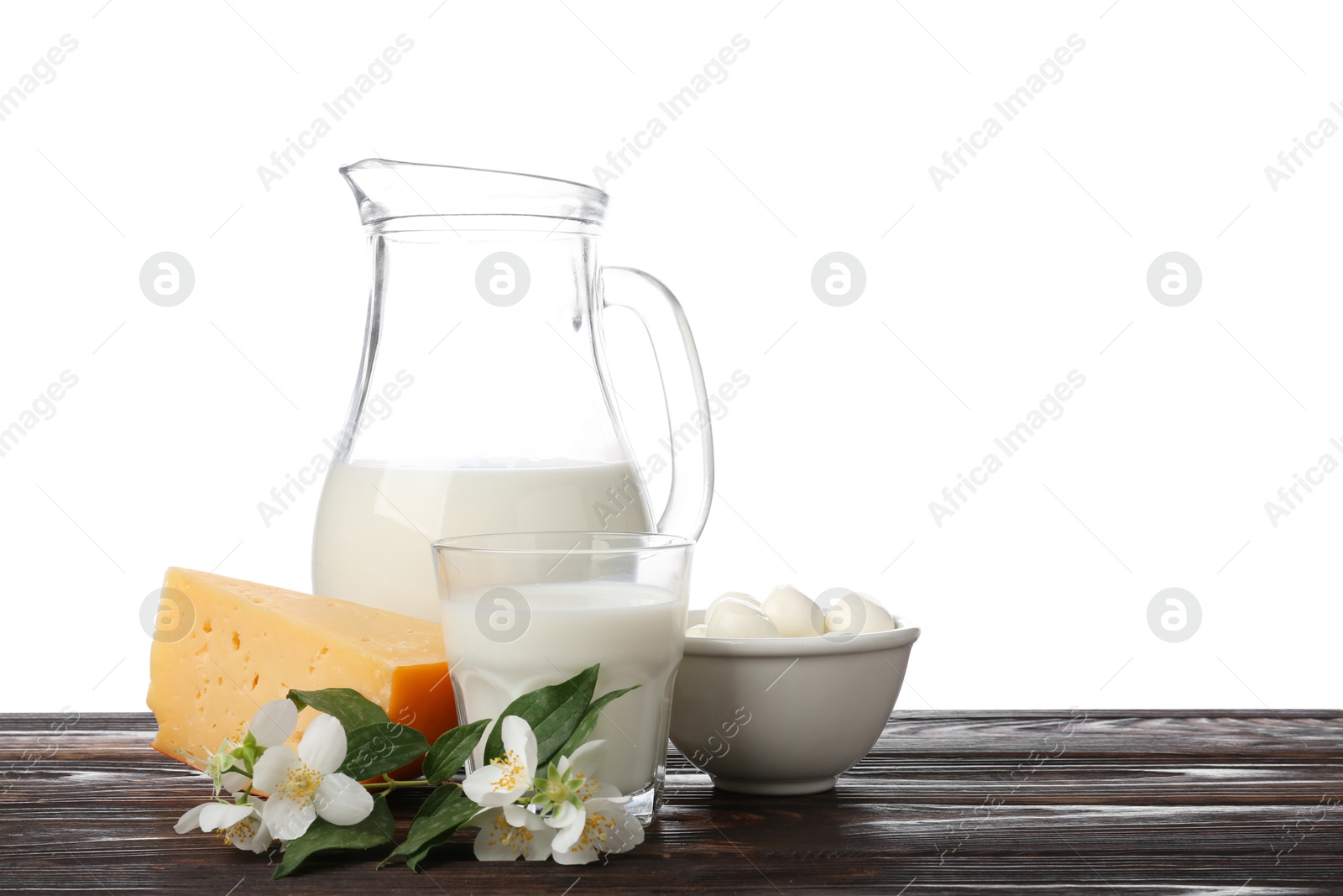 Different fresh dairy products and flowers on wooden table against white background Photo of Different fresh dairy products and flowers on wooden table against white background