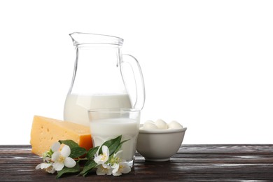 Photo of Different fresh dairy products and flowers on wooden table against white background