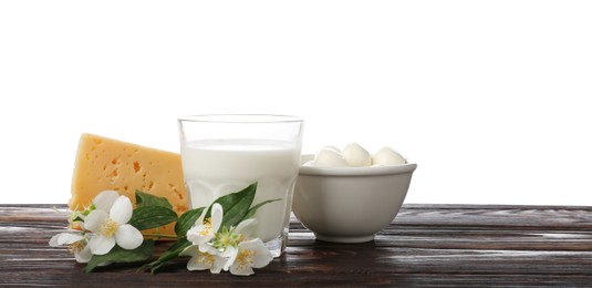 Photo of Different fresh dairy products and flowers on wooden table against white background