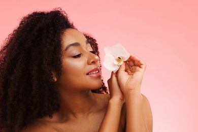 Photo of Portrait of beautiful Brazilian woman with orchid flower after spa treatment on pink gradient background