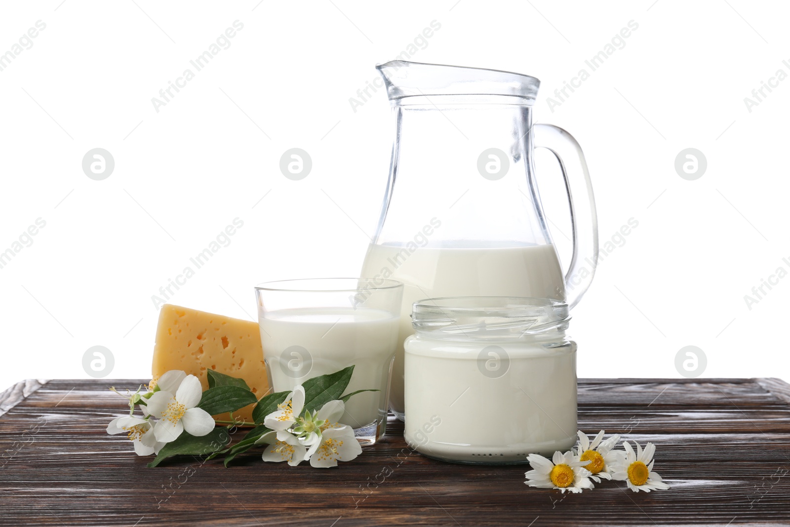 Photo of Different fresh dairy products and flowers on wooden table against white background