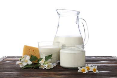Photo of Different fresh dairy products and flowers on wooden table against white background