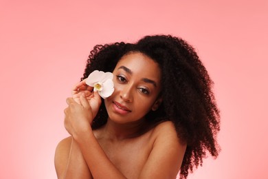 Photo of Portrait of beautiful Brazilian woman with orchid flower after spa treatment on pink gradient background