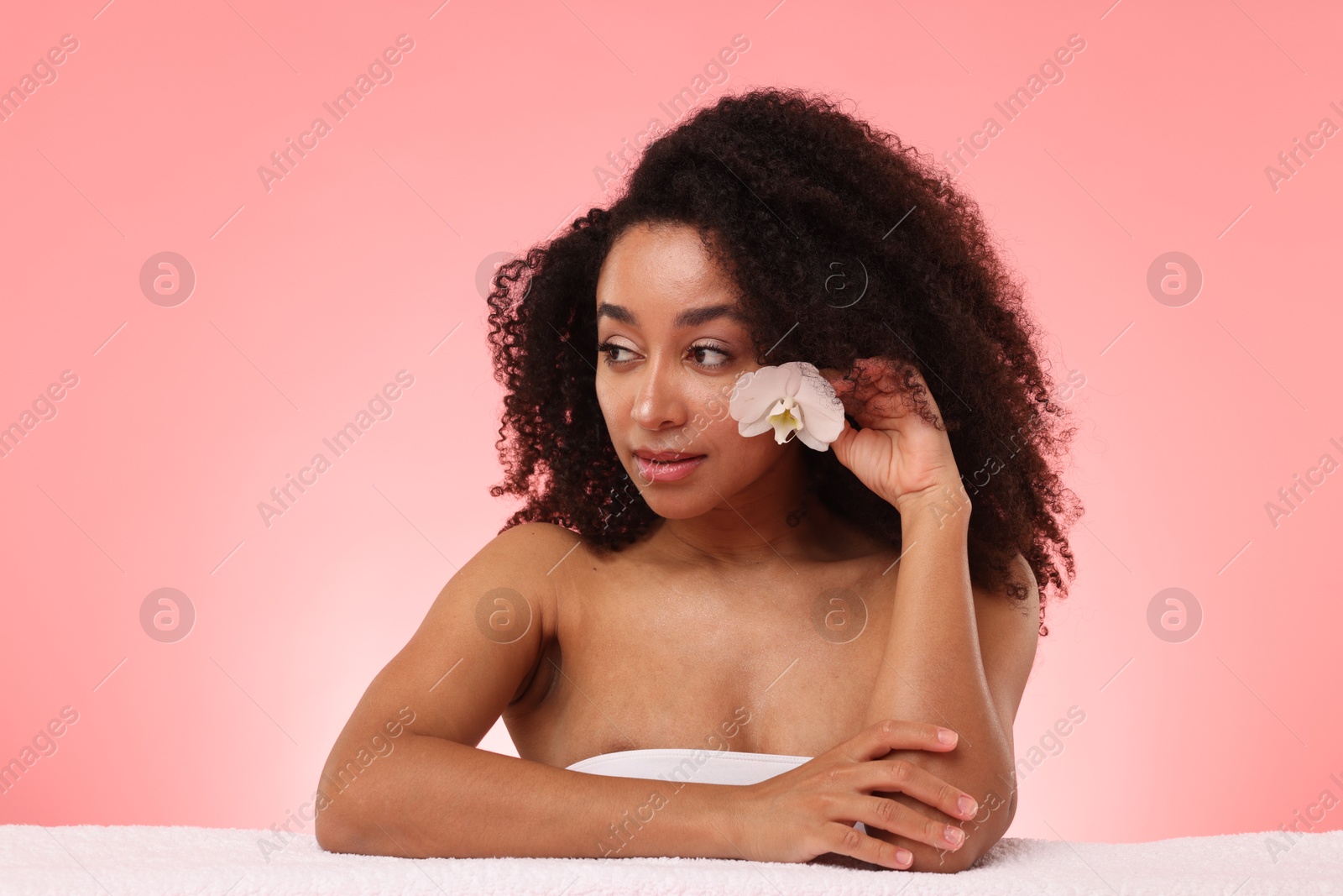 Portrait of beautiful Brazilian woman with orchid flower after spa treatment on pink gradient background Photo of Portrait of beautiful Brazilian woman with orchid flower after spa treatment on pink gradient background