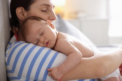 Photo of Mother putting her cute newborn baby to sleep at home, closeup