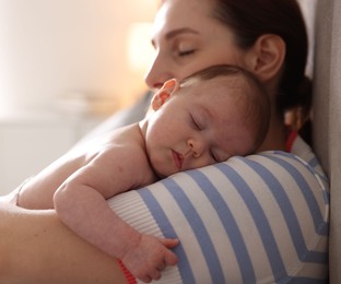 Photo of Mother putting her cute newborn baby to sleep at home, closeup
