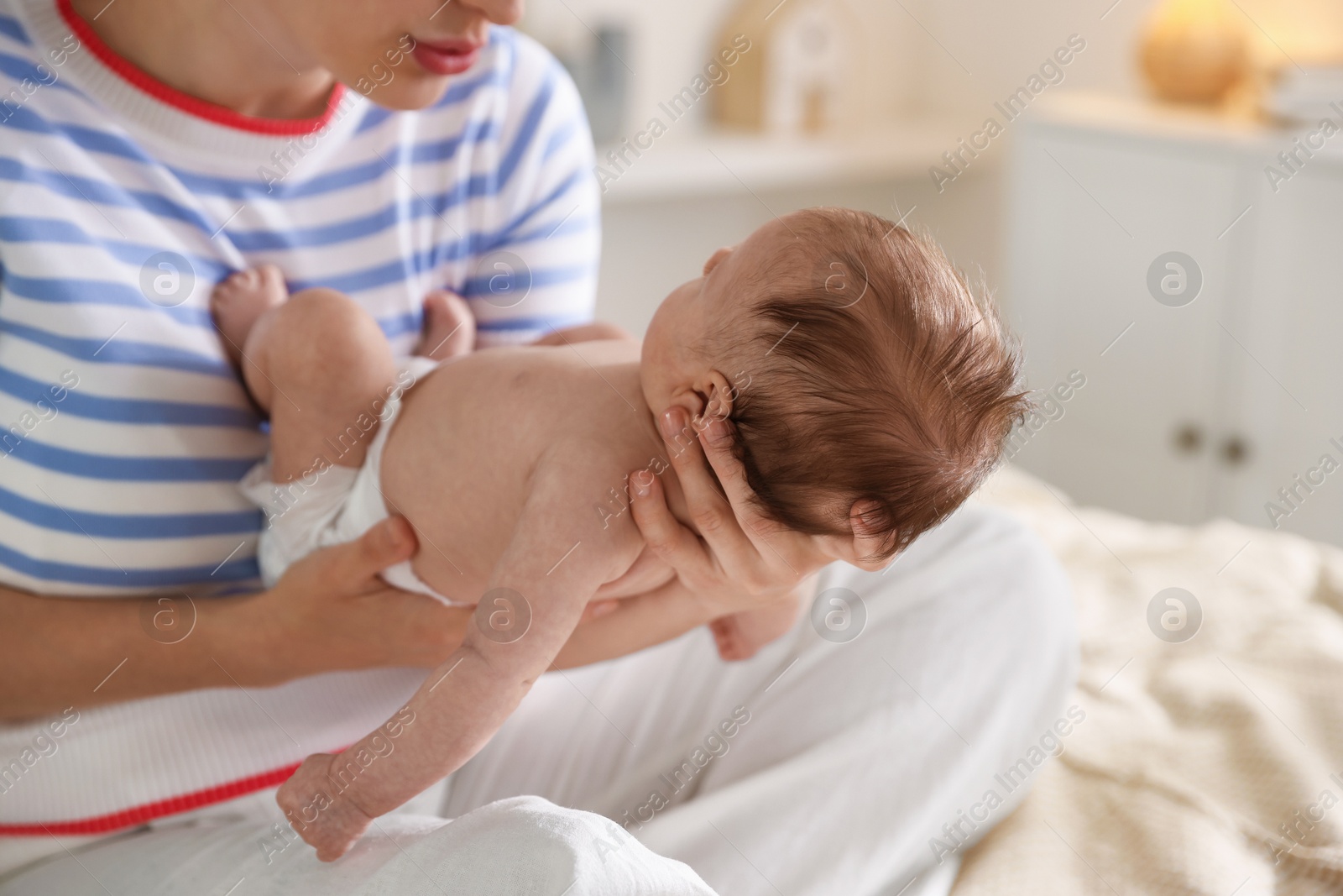 Mother putting her cute newborn baby to sleep on bed at home, closeup Photo of Mother putting her cute newborn baby to sleep on bed at home, closeup