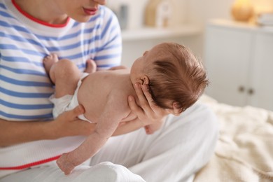 Photo of Mother putting her cute newborn baby to sleep on bed at home, closeup