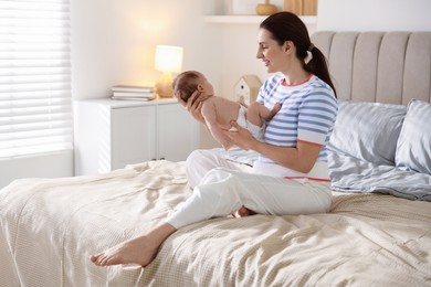 Photo of Mother putting her cute newborn baby to sleep on bed at home
