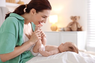 Photo of Mother with her cute newborn baby on bed at home