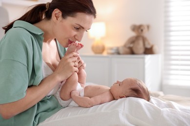 Photo of Mother with her cute newborn baby on bed at home
