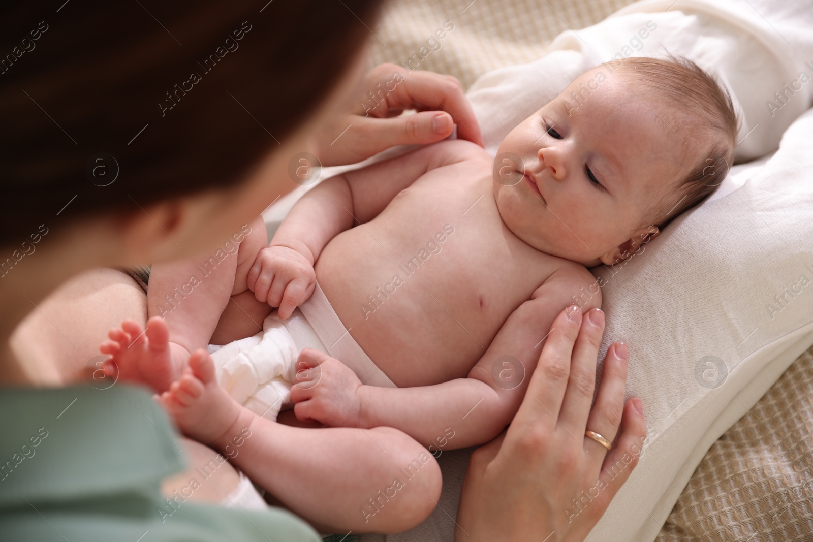 Mother putting her cute newborn baby to sleep on bed at home, above view Photo of Mother putting her cute newborn baby to sleep on bed at home, above view