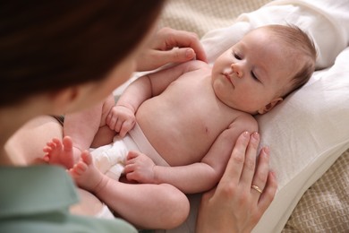 Photo of Mother putting her cute newborn baby to sleep on bed at home, above view