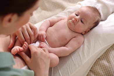 Photo of Mother putting her cute newborn baby to sleep on bed at home, above view