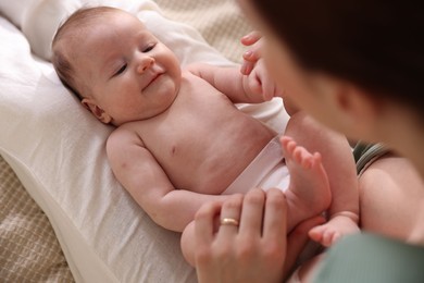 Photo of Mother putting her cute newborn baby to sleep on bed at home, above view