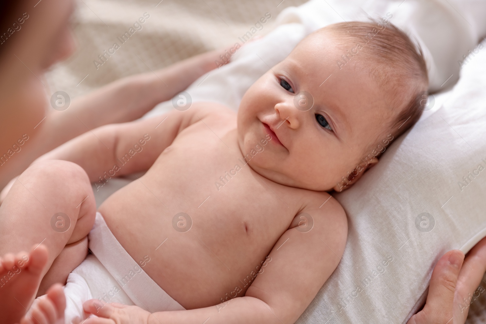 Mother putting her cute newborn baby to sleep on bed at home, above view Photo of Mother putting her cute newborn baby to sleep on bed at home, above view