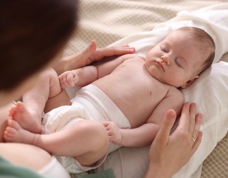 Photo of Mother putting her cute newborn baby to sleep on bed at home, above view