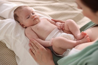 Photo of Mother putting her cute newborn baby to sleep on bed at home, above view