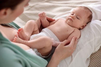 Photo of Mother putting her cute newborn baby to sleep on bed at home, above view