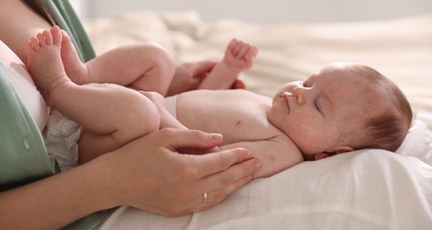 Photo of Mother putting her cute newborn baby to sleep at home, closeup