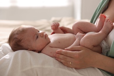 Photo of Mother putting her cute newborn baby to sleep at home, closeup