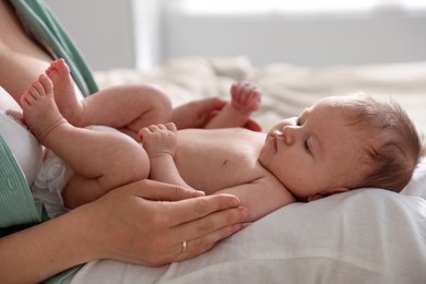 Photo of Mother putting her cute newborn baby to sleep at home, closeup