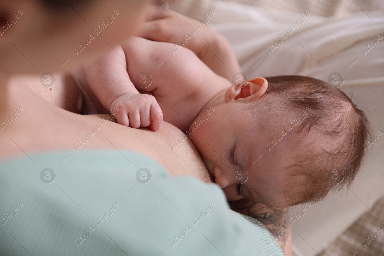 Mother breastfeeding her newborn baby indoors, above view Photo of Mother breastfeeding her newborn baby indoors, above view