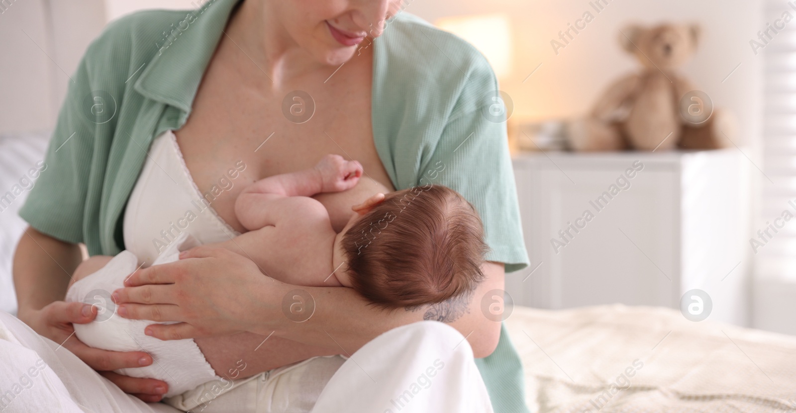 Mother breastfeeding her newborn baby indoors, closeup. Space for text Photo of Mother breastfeeding her newborn baby indoors, closeup. Space for text