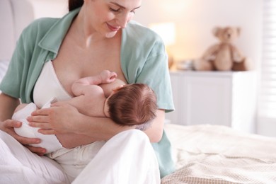 Photo of Mother breastfeeding her newborn baby on bed indoors