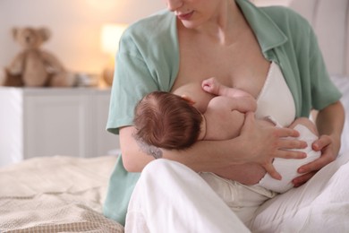 Photo of Mother breastfeeding her newborn baby indoors, closeup