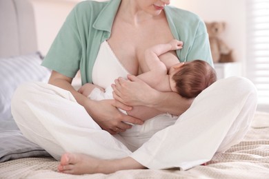 Photo of Mother breastfeeding her newborn baby indoors, closeup