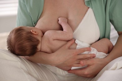 Photo of Mother breastfeeding her newborn baby indoors, closeup