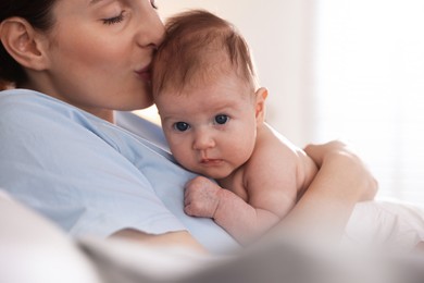Photo of Mother putting her cute newborn baby to sleep at home, closeup