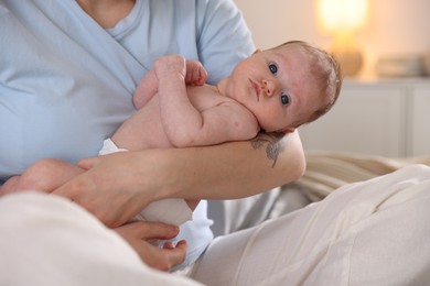 Photo of Mother putting her cute newborn baby to sleep at home, closeup