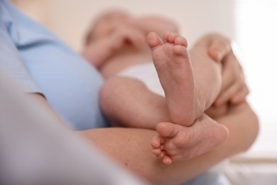 Photo of Mother putting her cute newborn baby to sleep at home, closeup