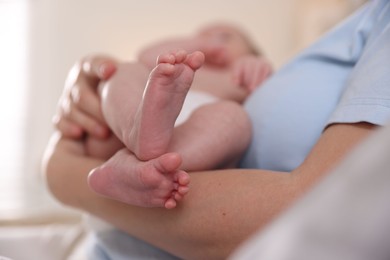 Photo of Mother putting her cute newborn baby to sleep at home, closeup