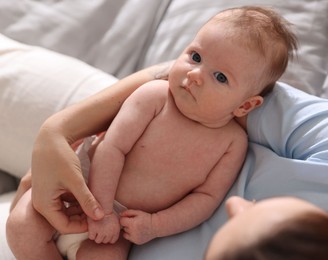 Photo of Mother putting her cute newborn baby to sleep on bed at home, above view