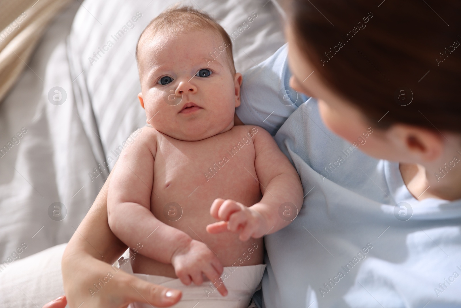 Mother putting her cute newborn baby to sleep on bed at home, above view Photo of Mother putting her cute newborn baby to sleep on bed at home, above view