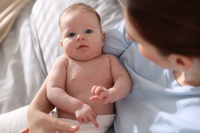 Photo of Mother putting her cute newborn baby to sleep on bed at home, above view
