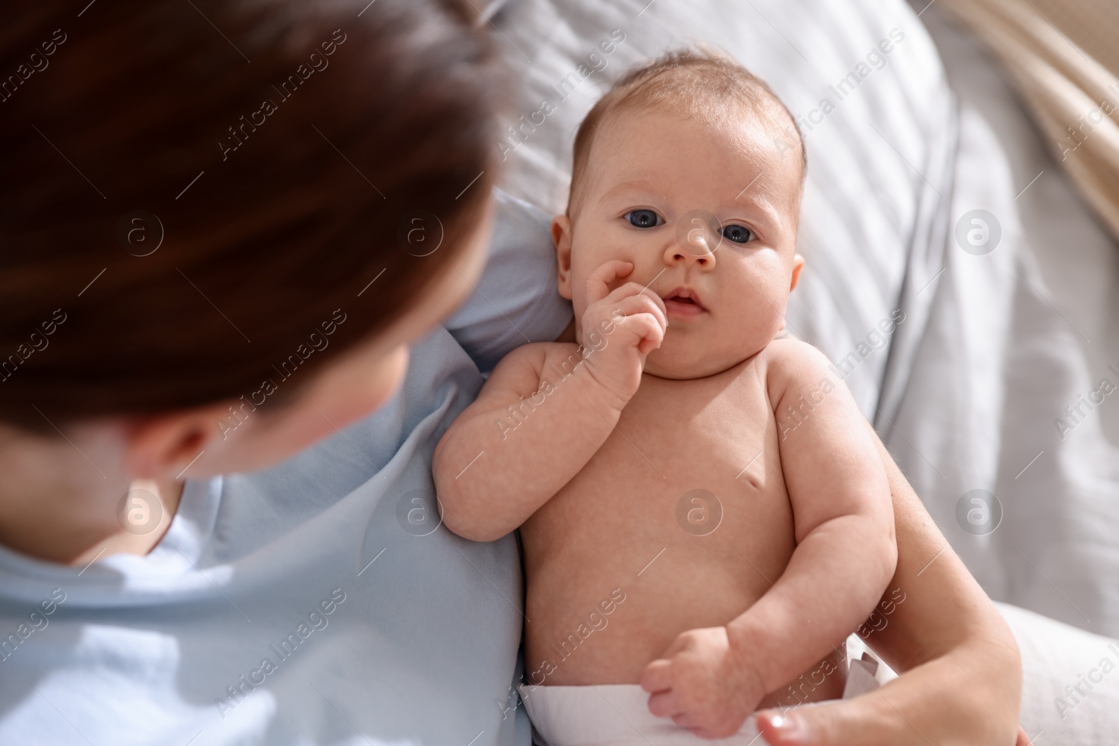 Mother putting her cute newborn baby to sleep on bed at home, above view Photo of Mother putting her cute newborn baby to sleep on bed at home, above view
