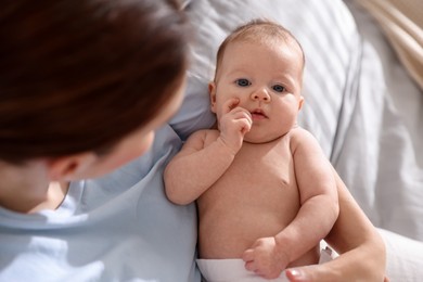 Photo of Mother putting her cute newborn baby to sleep on bed at home, above view