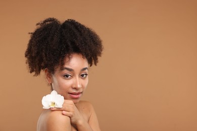 Photo of Portrait of beautiful Brazilian woman with orchid flower after spa treatment on light brown background. Space for text