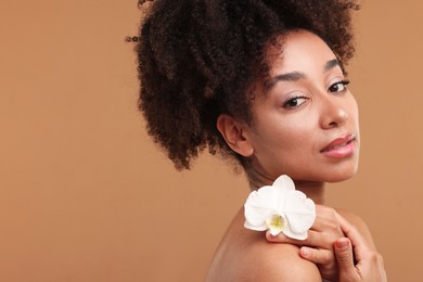 Photo of Portrait of beautiful Brazilian woman with orchid flower after spa treatment on light brown background. Space for text