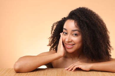 Photo of Portrait of beautiful Brazilian woman after spa treatment at bamboo table on beige gradient background