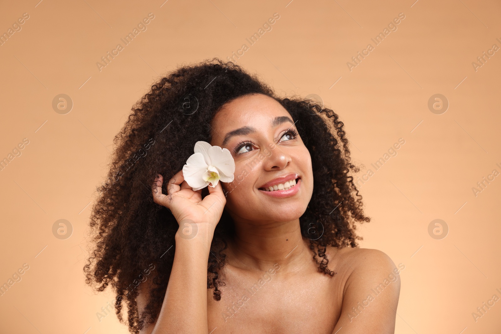 Portrait of beautiful Brazilian woman with orchid flower after spa treatment on beige background Photo of Portrait of beautiful Brazilian woman with orchid flower after spa treatment on beige background