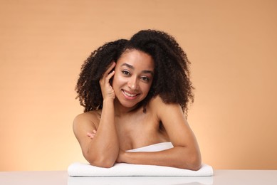 Photo of Portrait of beautiful Brazilian woman with towel after spa treatment on beige gradient background