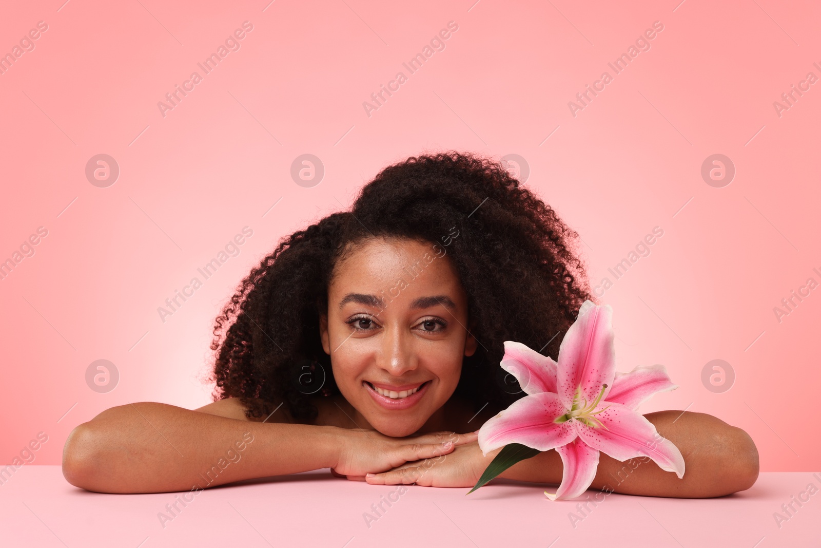 Portrait of beautiful Brazilian woman with lily flower after spa treatment on pink gradient background Photo of Portrait of beautiful Brazilian woman with lily flower after spa treatment on pink gradient background