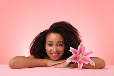 Photo of Portrait of beautiful Brazilian woman with lily flower after spa treatment on pink gradient background
