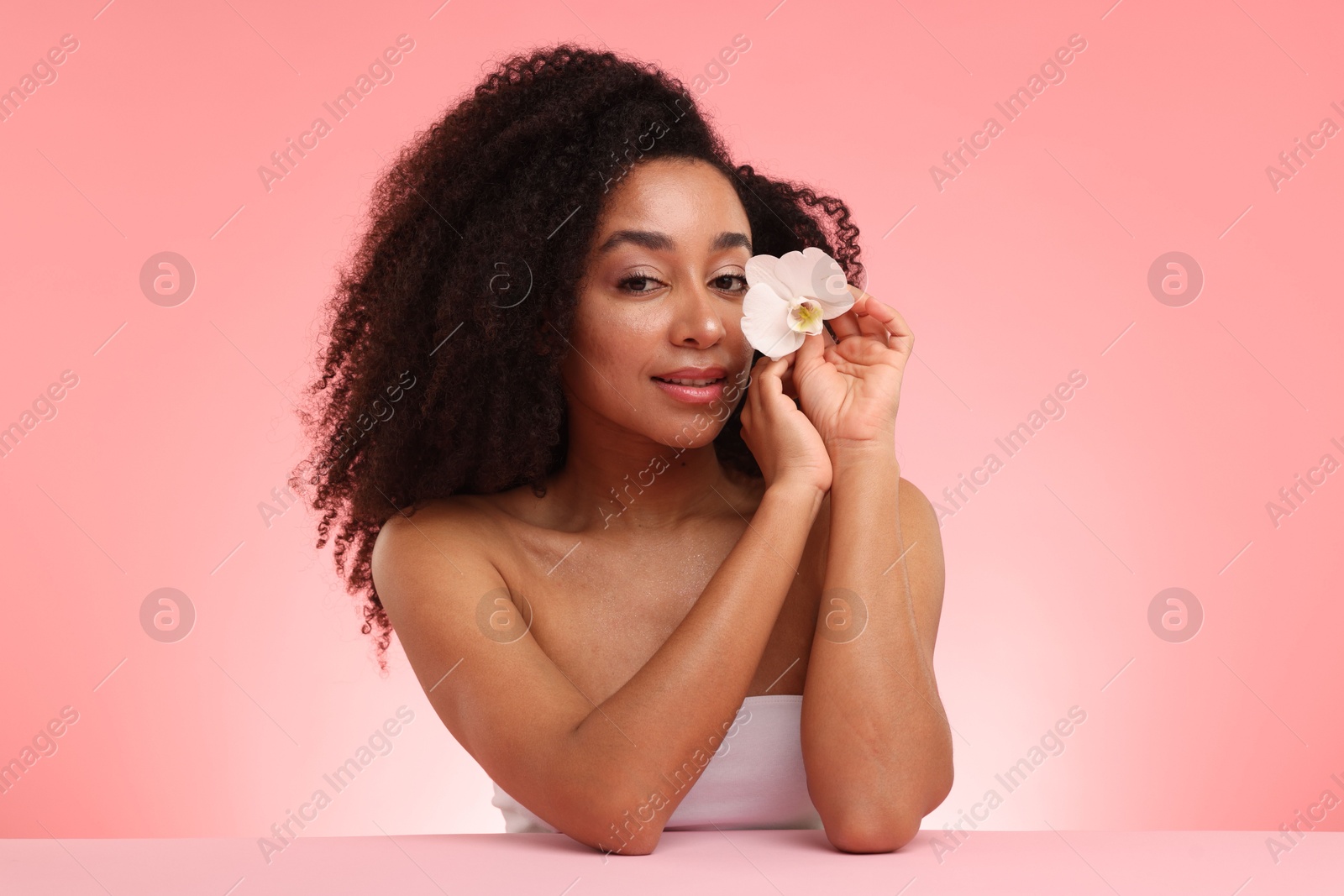 Portrait of beautiful Brazilian woman with orchid flower after spa treatment on pink gradient background Photo of Portrait of beautiful Brazilian woman with orchid flower after spa treatment on pink gradient background