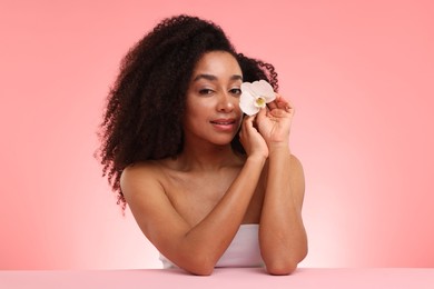 Photo of Portrait of beautiful Brazilian woman with orchid flower after spa treatment on pink gradient background